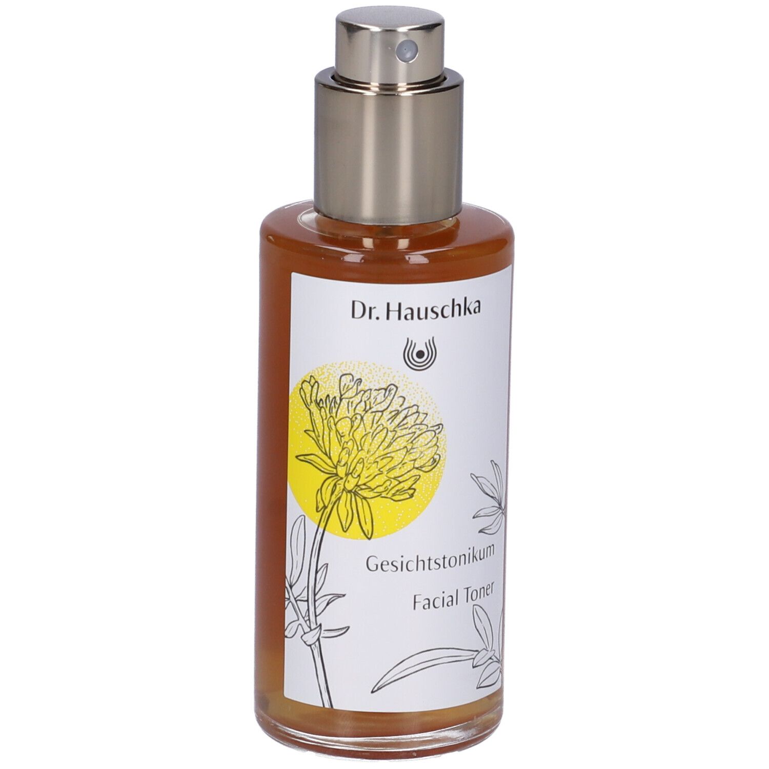 Flacone di vetro marrone con vaporizzatore. Etichetta con nome del prodotto e design floreale. Dr. Hauschka Facial Toner.