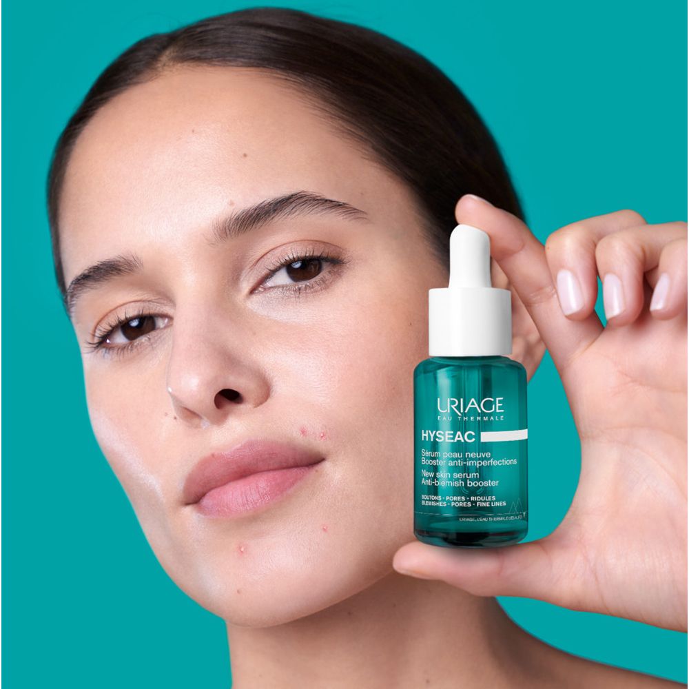 Donna che tiene in mano un flacone verde. Testo: Uriage, Hyseac, Siero peau neuve, Booster anti-imperfections.