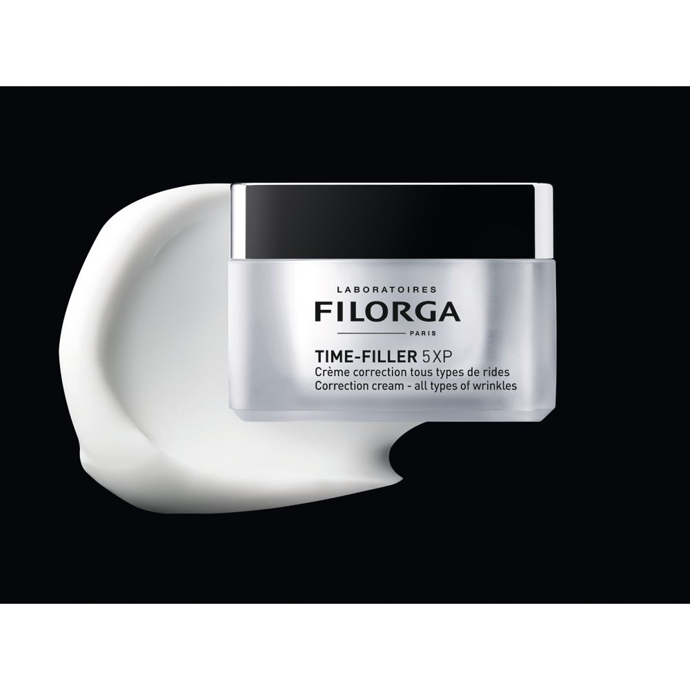 Cremebehälter mit Deckel. Aufschrift: FILORGA, TIME-FILLER 5XP. Text: Crème correction tous types de rides. Creme auf schwarzem Hintergrund.