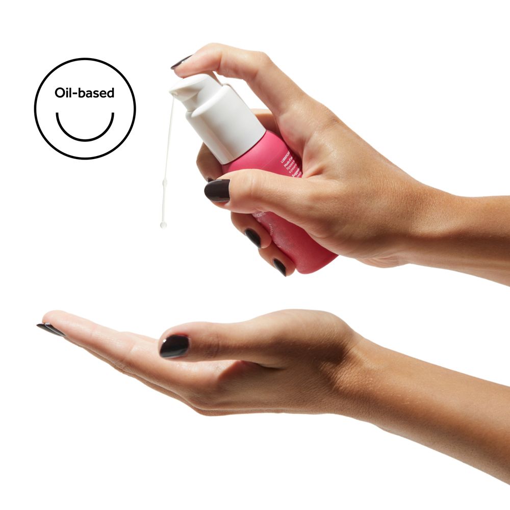 Mani che tengono flacone rosa con dispenser bianco. Gocce di liquido. Logo: Oil-based.