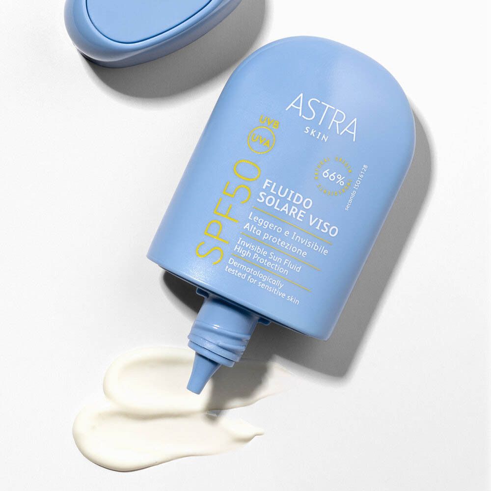 Flacone azzurro, prodotto accanto. Scritta SPF50 gialla. Scritta: ASTRA SKIN, FLUIDO SOLARE VISO, 66%.