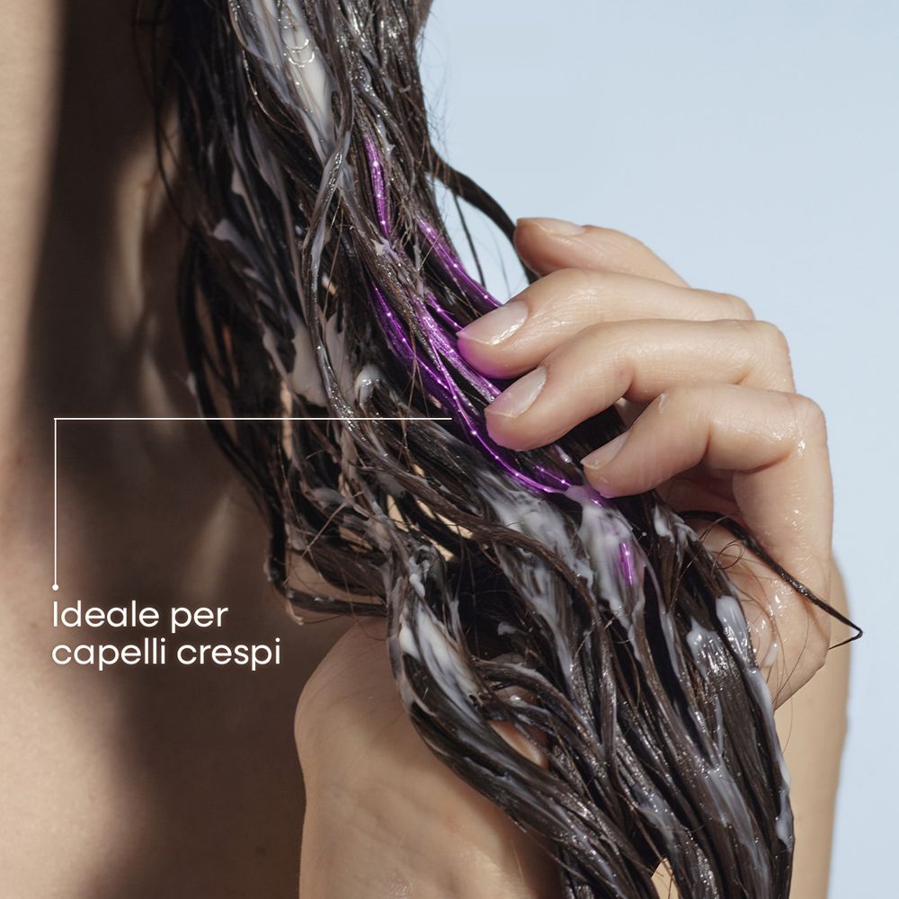 Capelli scuri con crema bianca e ciocche viola scintillanti, tenuti da una mano.