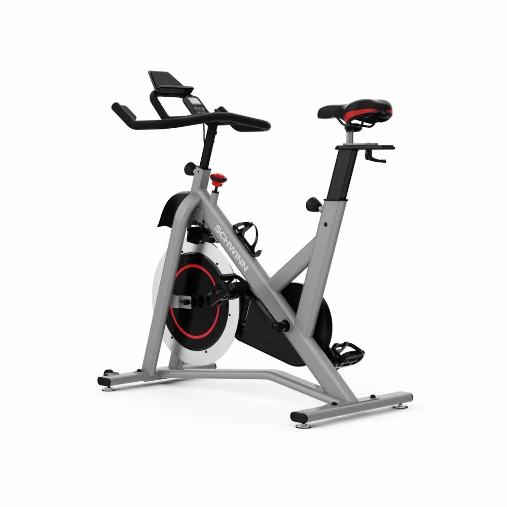Grauer Heimtrainer mit rotem Akzent. Schwarzes Schwungrad, Lenker, Sattel und Pedale. Marke: Schwinn. Wasserflaschenhalterung.