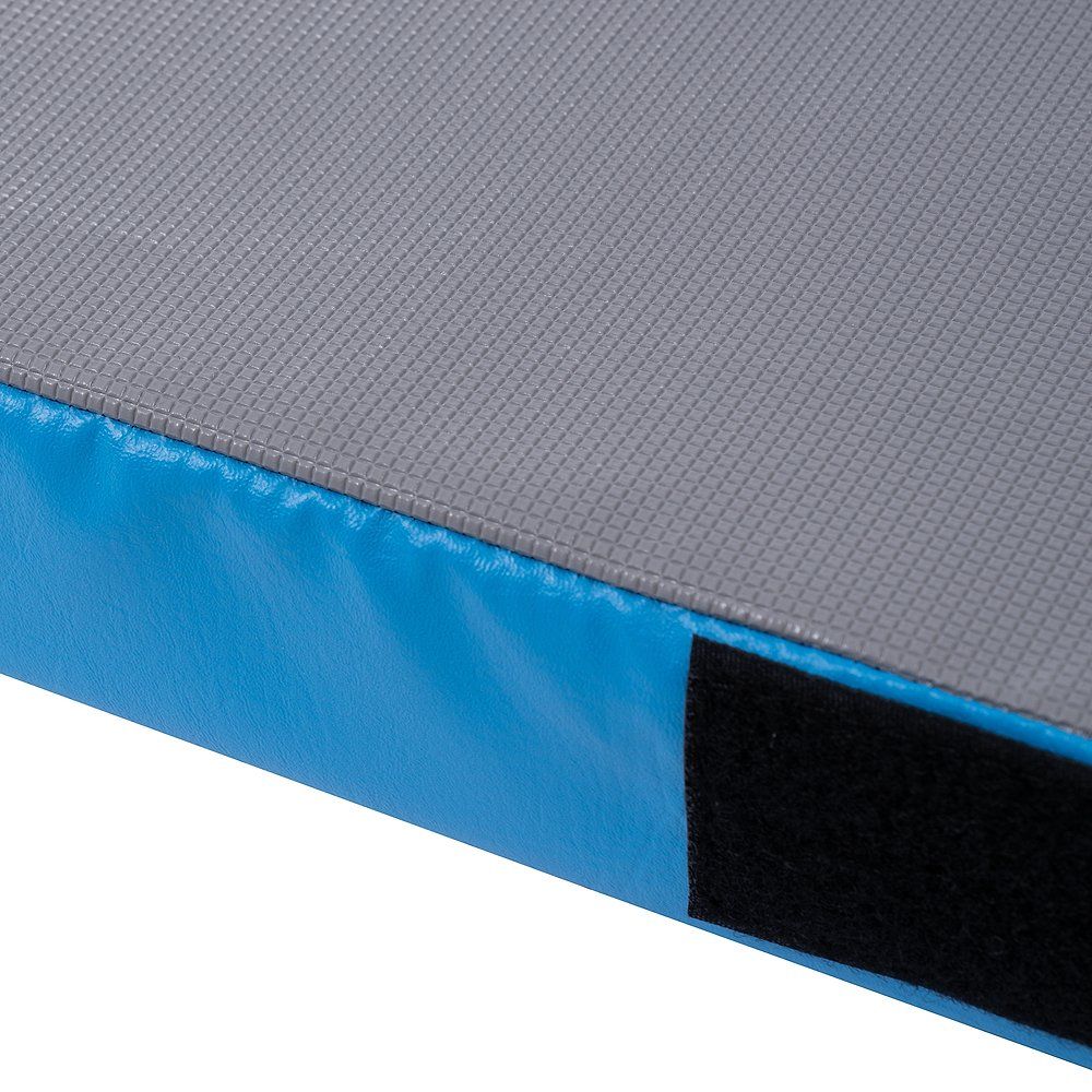 Nahaufnahme einer blauen Turnmatte mit grauem Obermaterial und einem schwarzen Klettverschluss an der Ecke.