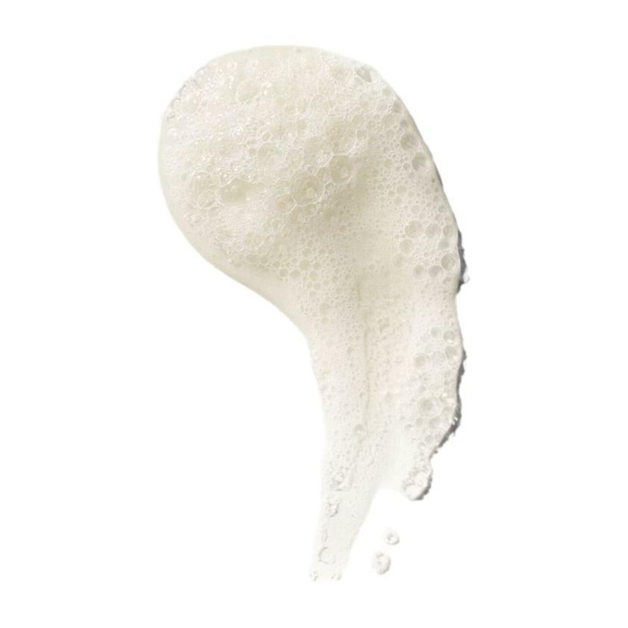 Nahaufnahme von Schaum. Cremefarbener Schaum, der sich auf weißem Hintergrund ausbreitet. Blasen sind sichtbar.