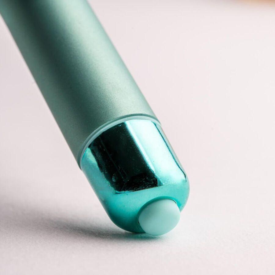 Nahaufnahme des Endes eines grünen, zylindrischen Wellness-Produkts. Mit blauem Knopf.