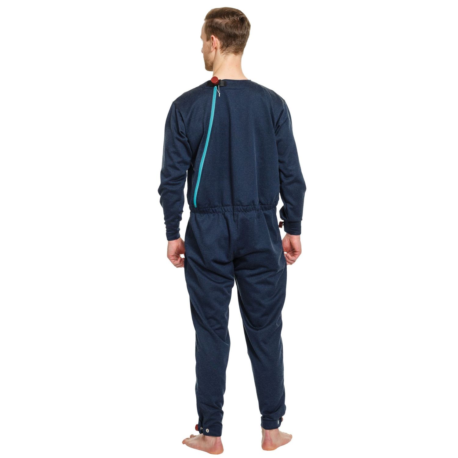Blauer Pflegeoverall von hinten. Reißverschluss am Rücken. Rote Akzente an den Bündchen. Mann steht vor weißem Hintergrund.