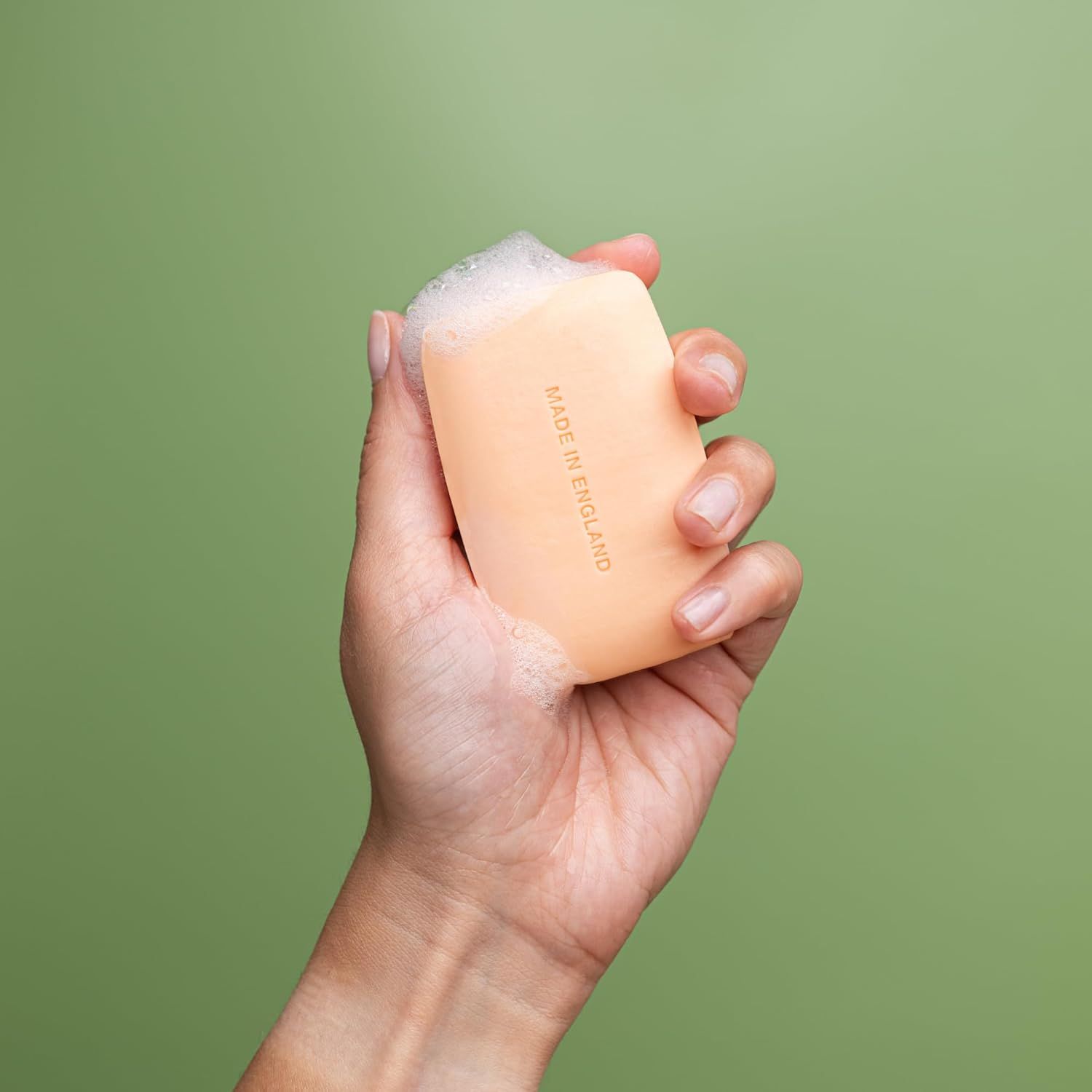 Helle Seife in einer Hand, mit Schaum bedeckt. Aufdruck "Made in England".