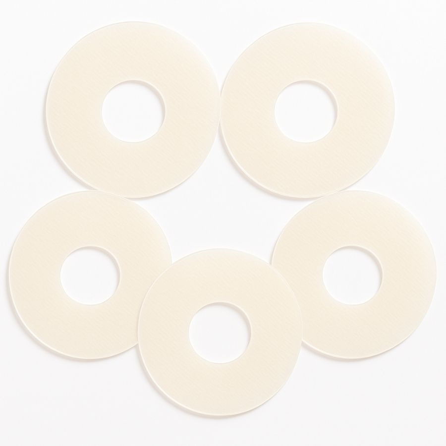 Fünf kreisförmige, beige Silikonpflaster mit zentralem Loch, angeordnet wie Blütenblätter.