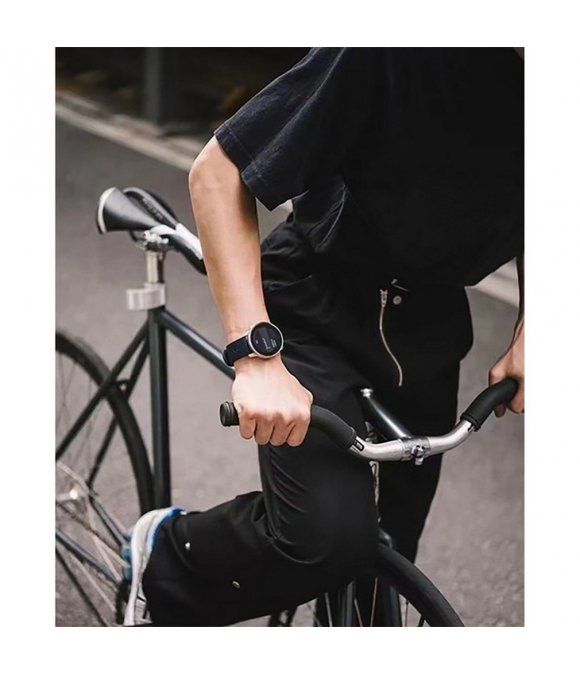 Person mit schwarzem Outfit, die ein Fahrrad fährt. Am Handgelenk eine runde Smartwatch mit dunklem Armband.