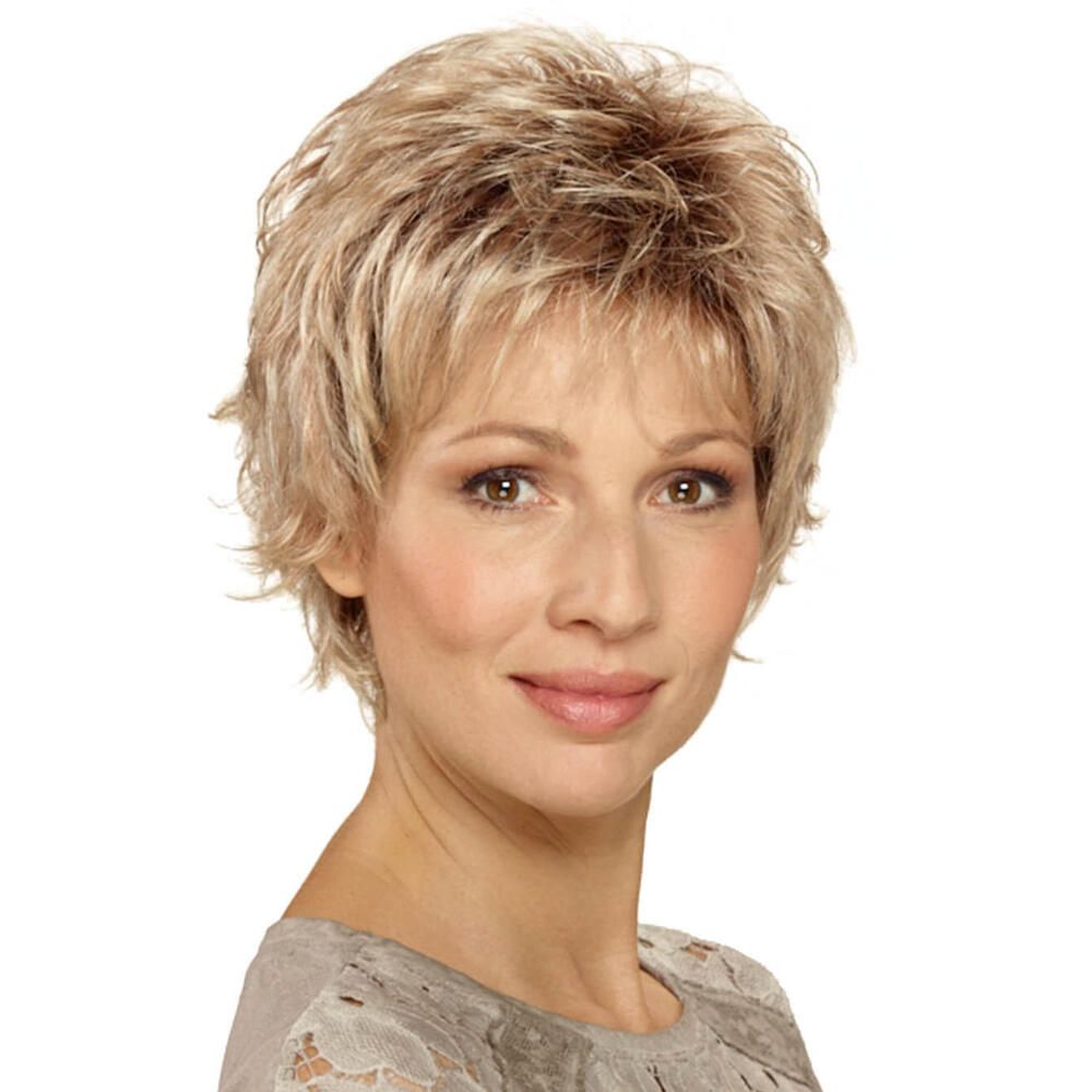 Kurzhaarperücke in Blondtönen. Die Frau trägt ein graues Oberteil. Frontansicht.