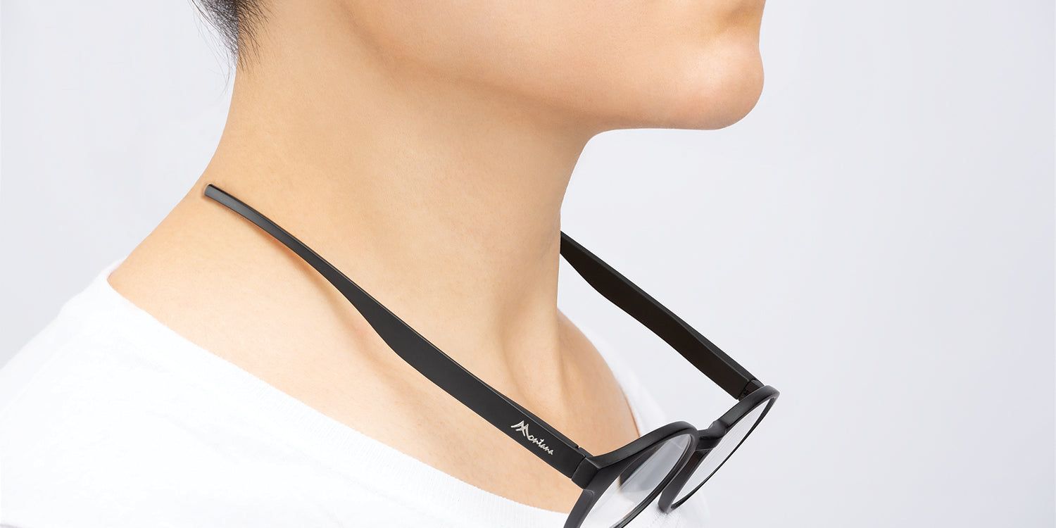 Person trägt eine schwarze Brille um den Hals. Die Brille ist am Nacken befestigt.