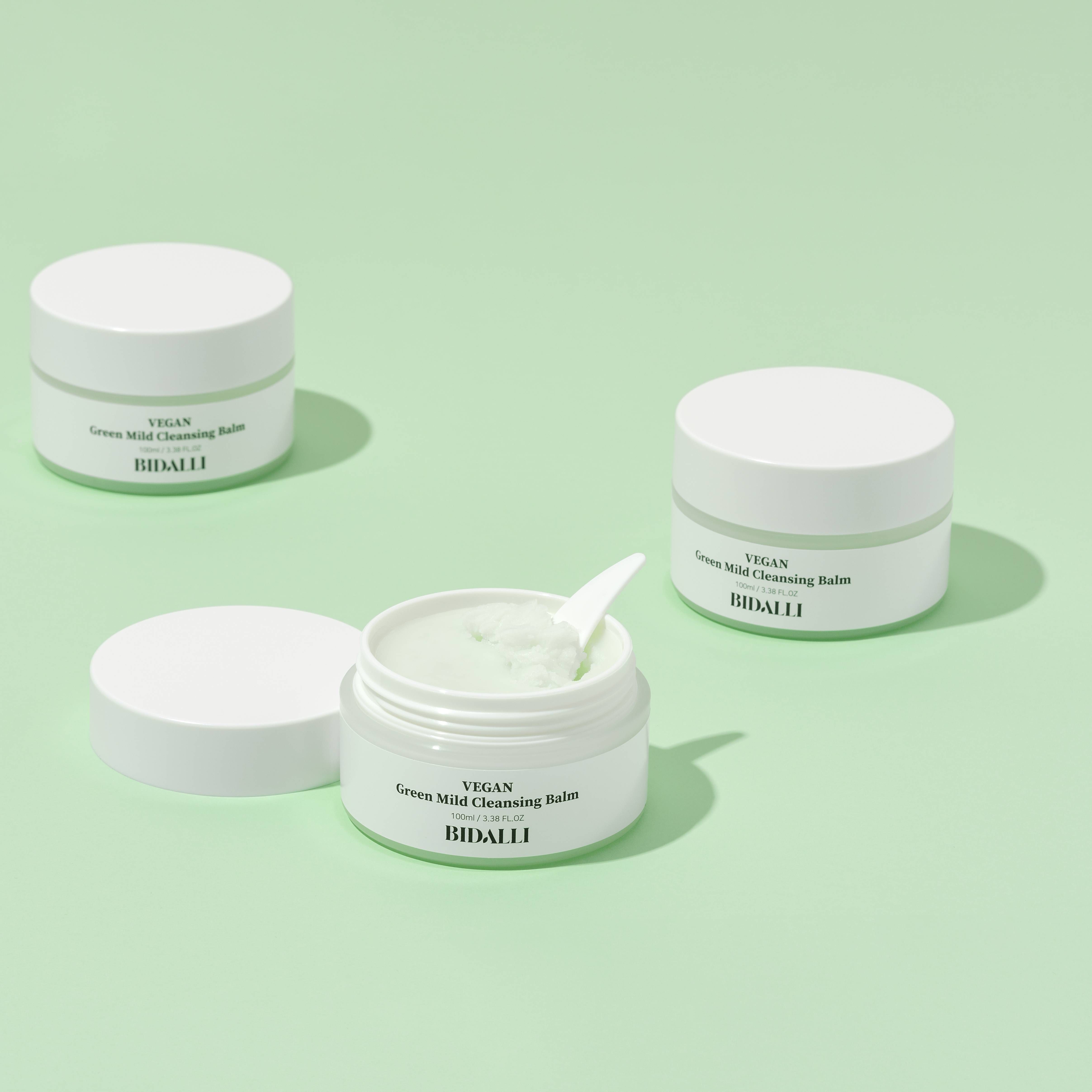 Drei Tiegel mit Deckel. Einer ist geöffnet mit grünem Balsam und Spatel. Auf den Etiketten steht: VEGAN Green Mild Cleansing Balm. BIDALLI.