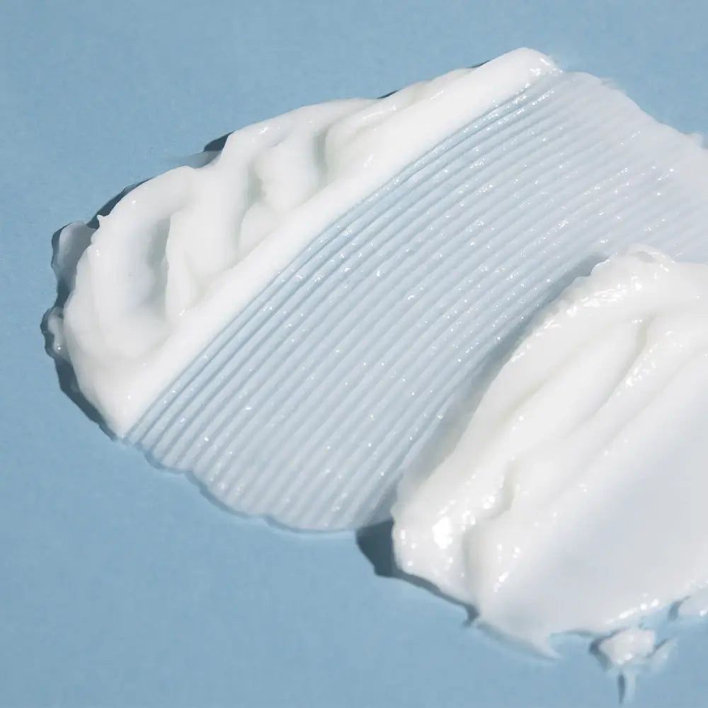 Nahaufnahme von weißer Creme auf blauem Hintergrund. Creme mit geriffelter und glatter Textur.