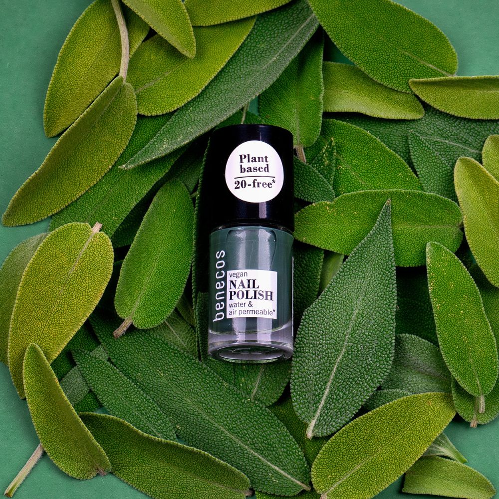 Benecos veganer Nagellack 'sage green' in Glasflasche, umgeben von Salbeiblättern.