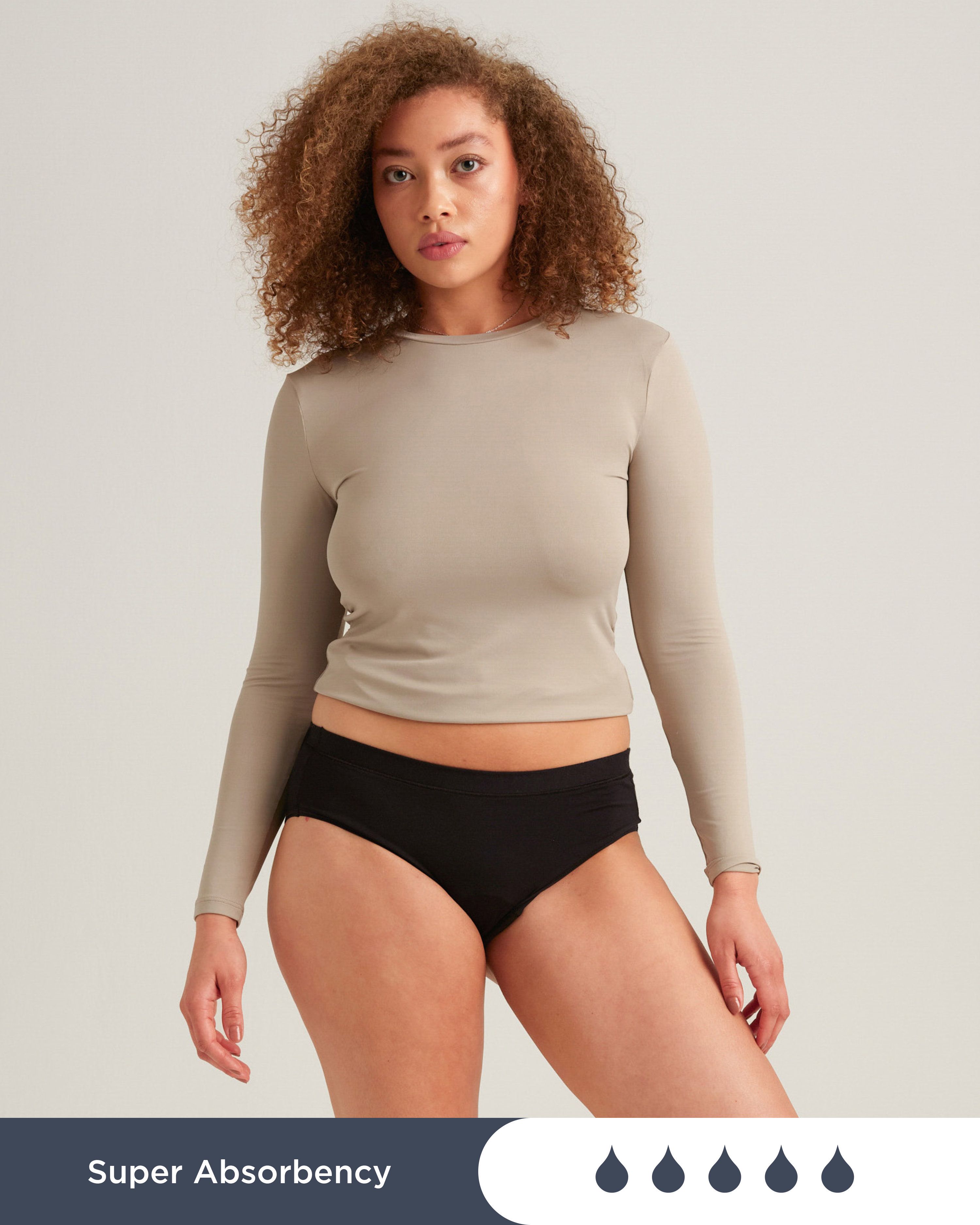 Schwarzer Saalt Comfort Brief. Text: Super Absorbency. Vier Tropfen-Symbole. Frau trägt Unterwäsche und Oberteil.