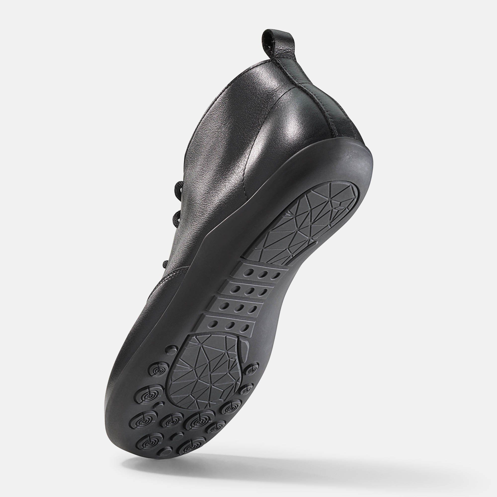 Schwarze Stiefelette, Unterseite. Flache Sohle mit Profil. Ferse nach oben.