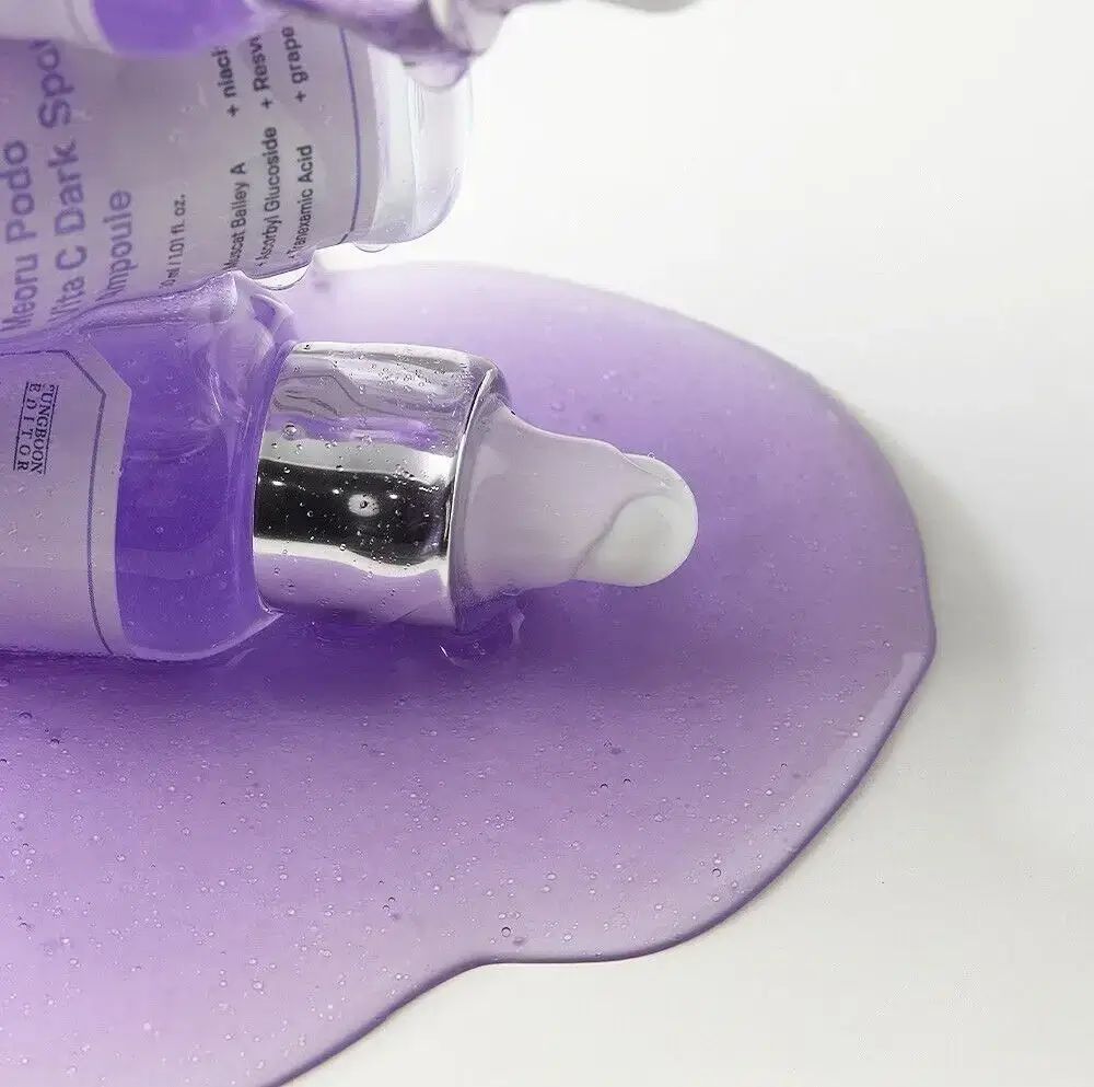 Violette Flüssigkeit auf weißem Untergrund. Flaschen mit Pipetten. Produktnamen auf den Etiketten sichtbar.