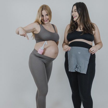 Zwei Frauen, eine schwanger, eine mit Bauchgurt. Eine hält eine rosa Intimdusche.
