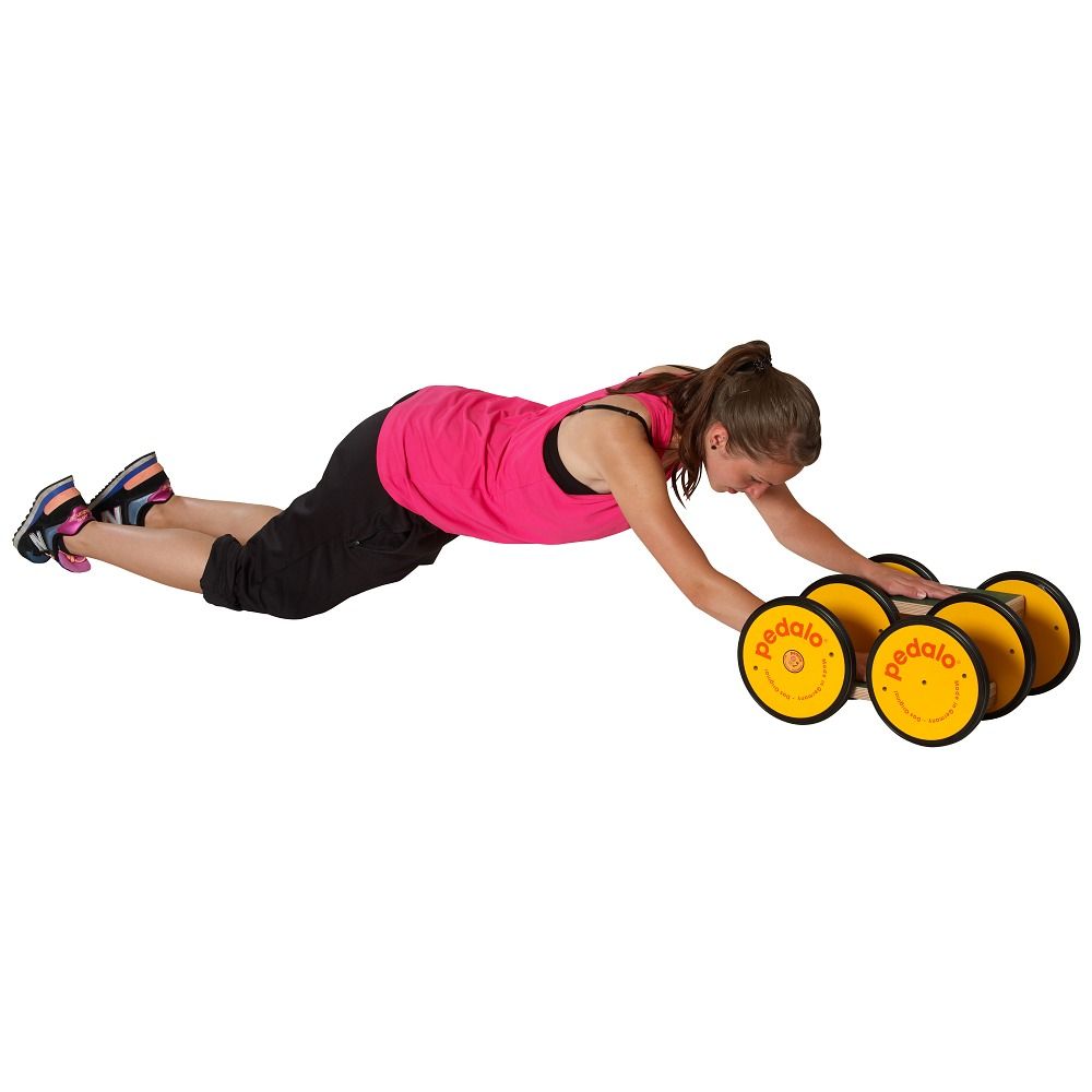 Frau auf dem Bauch liegend, stützt sich auf Koordinationstrainer ab. Gelbe Räder mit "pedalo"-Logo. Sie trägt Sportkleidung.