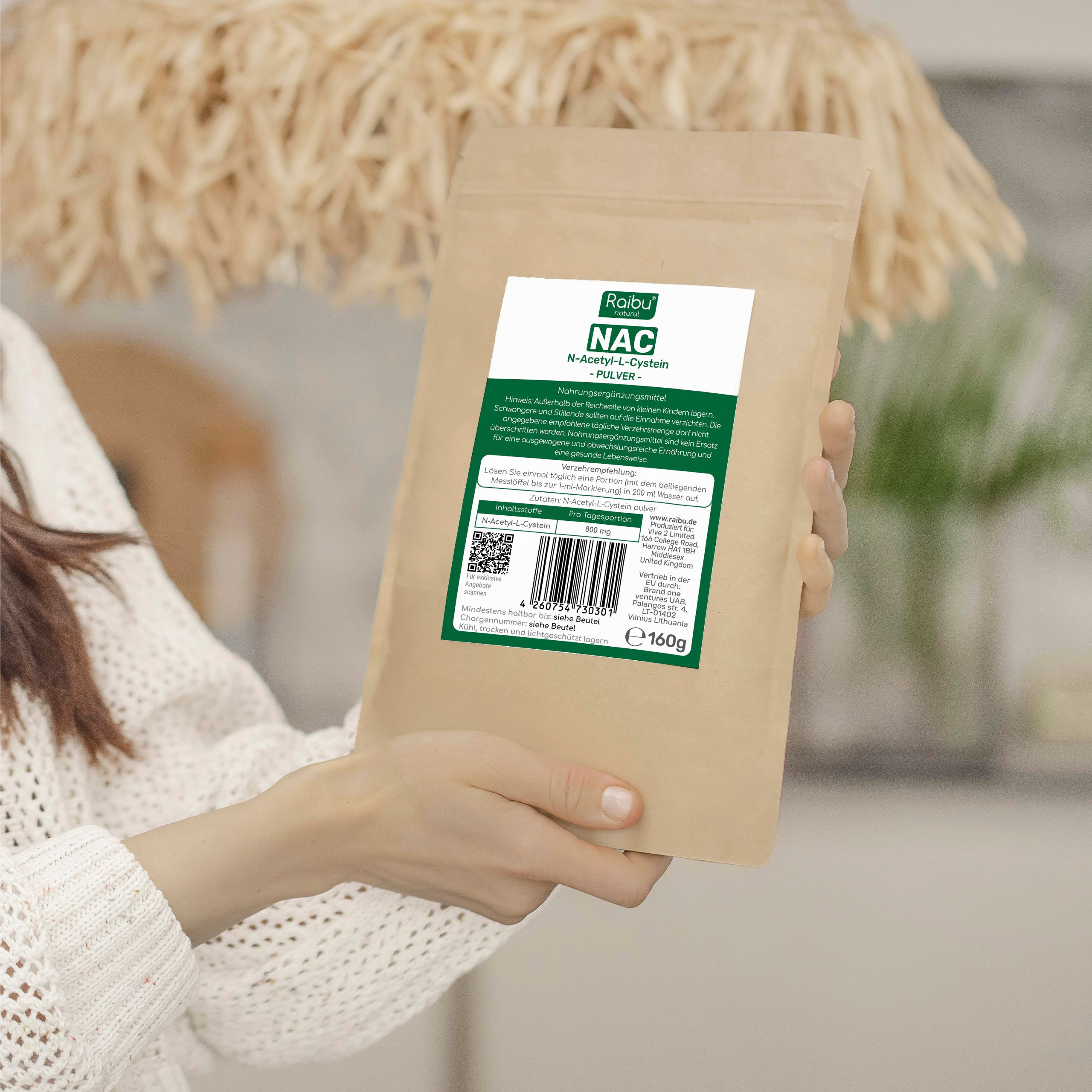Person hält eine braune Tüte mit weißem Etikett. Aufschrift: Raibu natural NAC N-Acetyl-L-Cystein Pulver. Enthält 160g. QR-Code und Barcode.