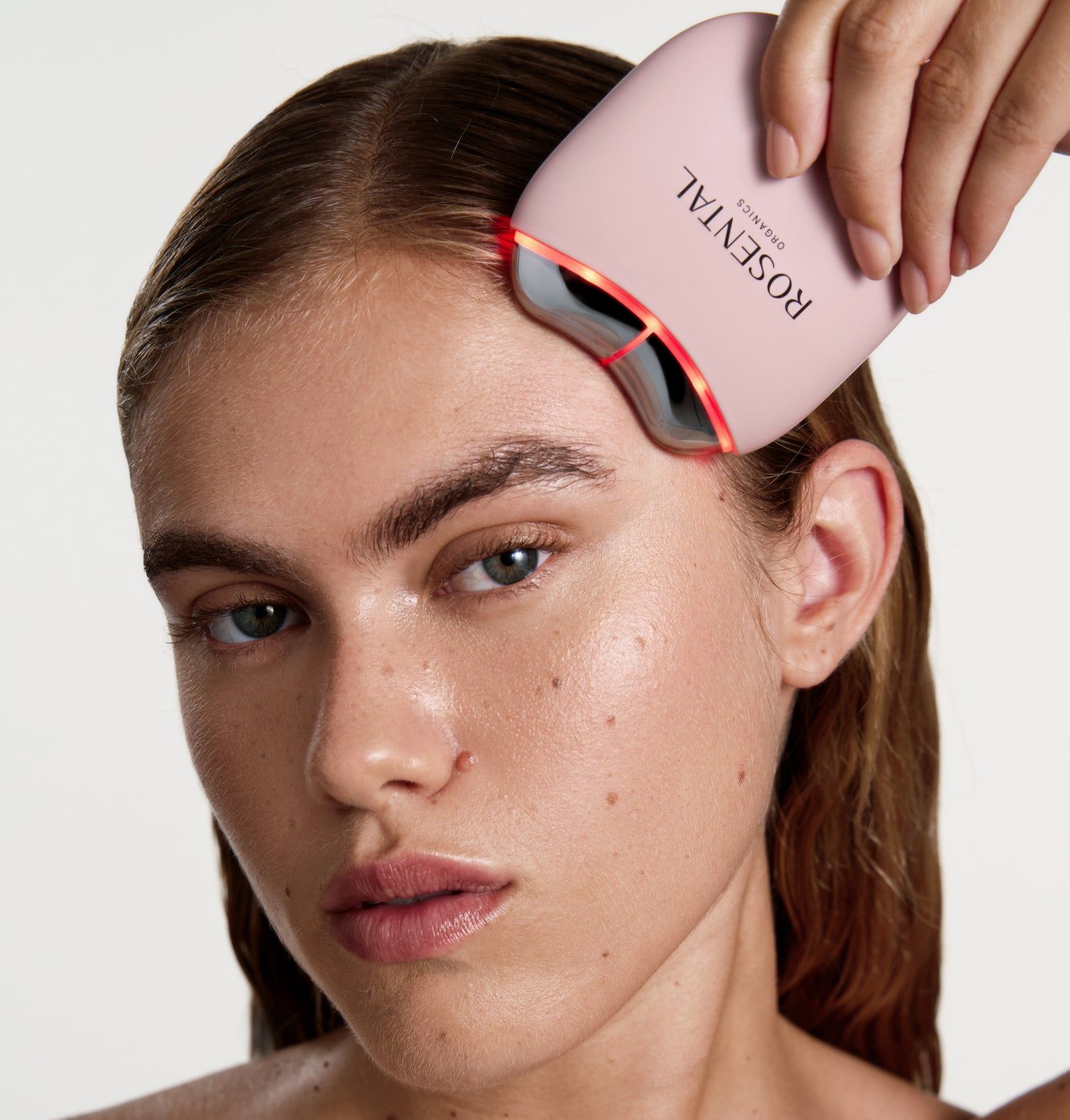 Rosa Gerät mit der Aufschrift "ROSENTAL". Das Gerät wird auf der Haut einer Person verwendet. Rote Lichter sind sichtbar.