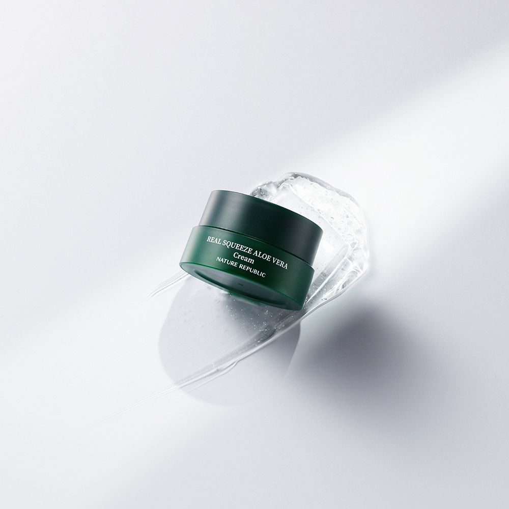 Grüner Tiegel NATURE REPUBLIC Real Squeeze Aloe Vera Cream auf weißem Untergrund mit Wasser. Aufschrift: Real Squeeze Aloe Vera Cream.