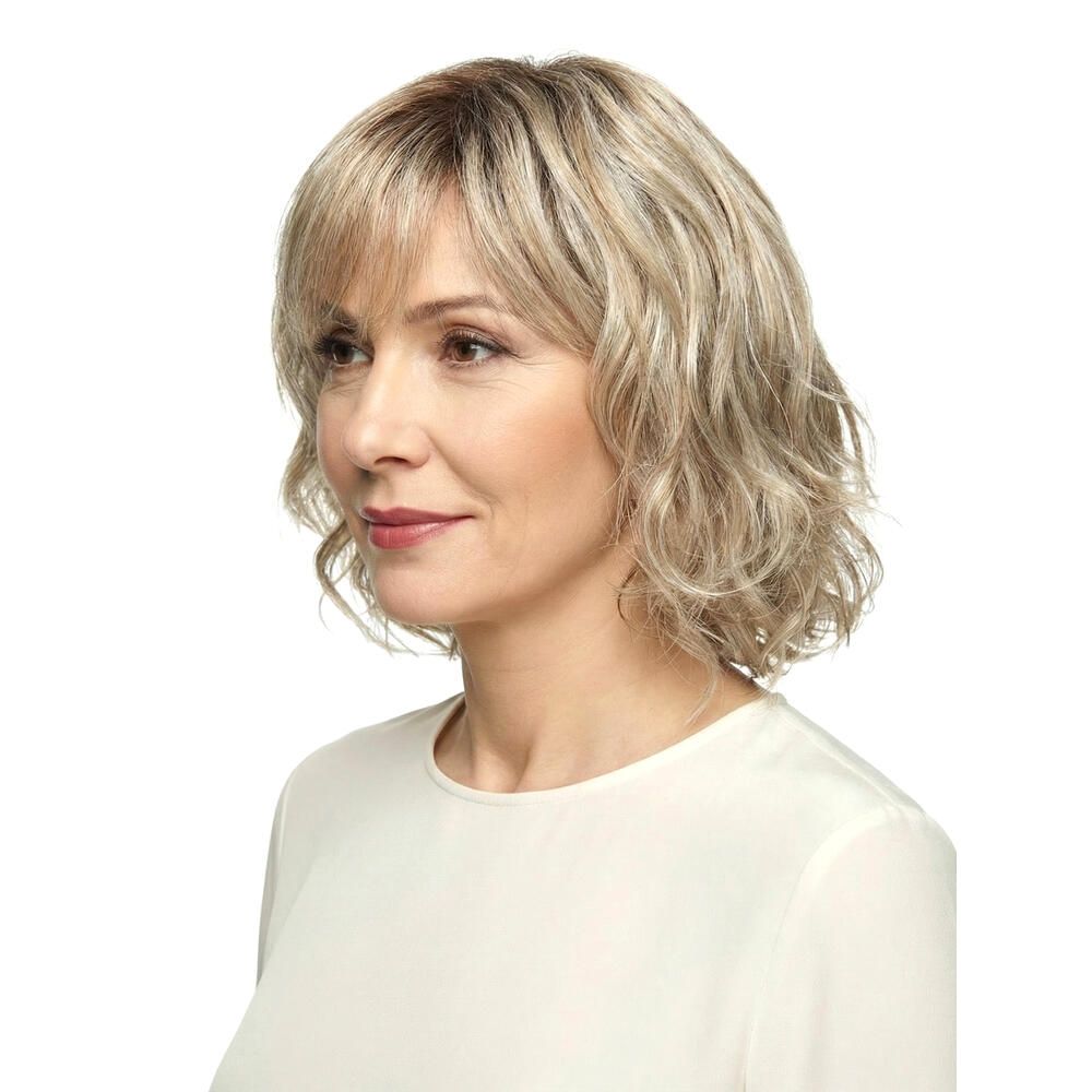 Perücke Capri von DELUXE. Blond gewellt, mit Pony. Frau mit Perücke, Seitenansicht.