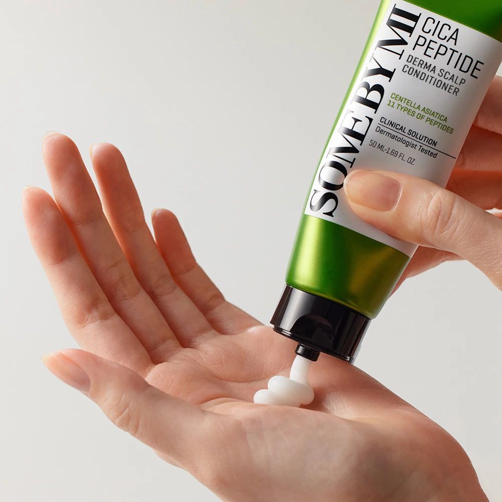Grüne Tube SOME BY MI Cica Peptide. Produkt wird auf Hand gedrückt. Weiße Creme kommt aus der Tube.
