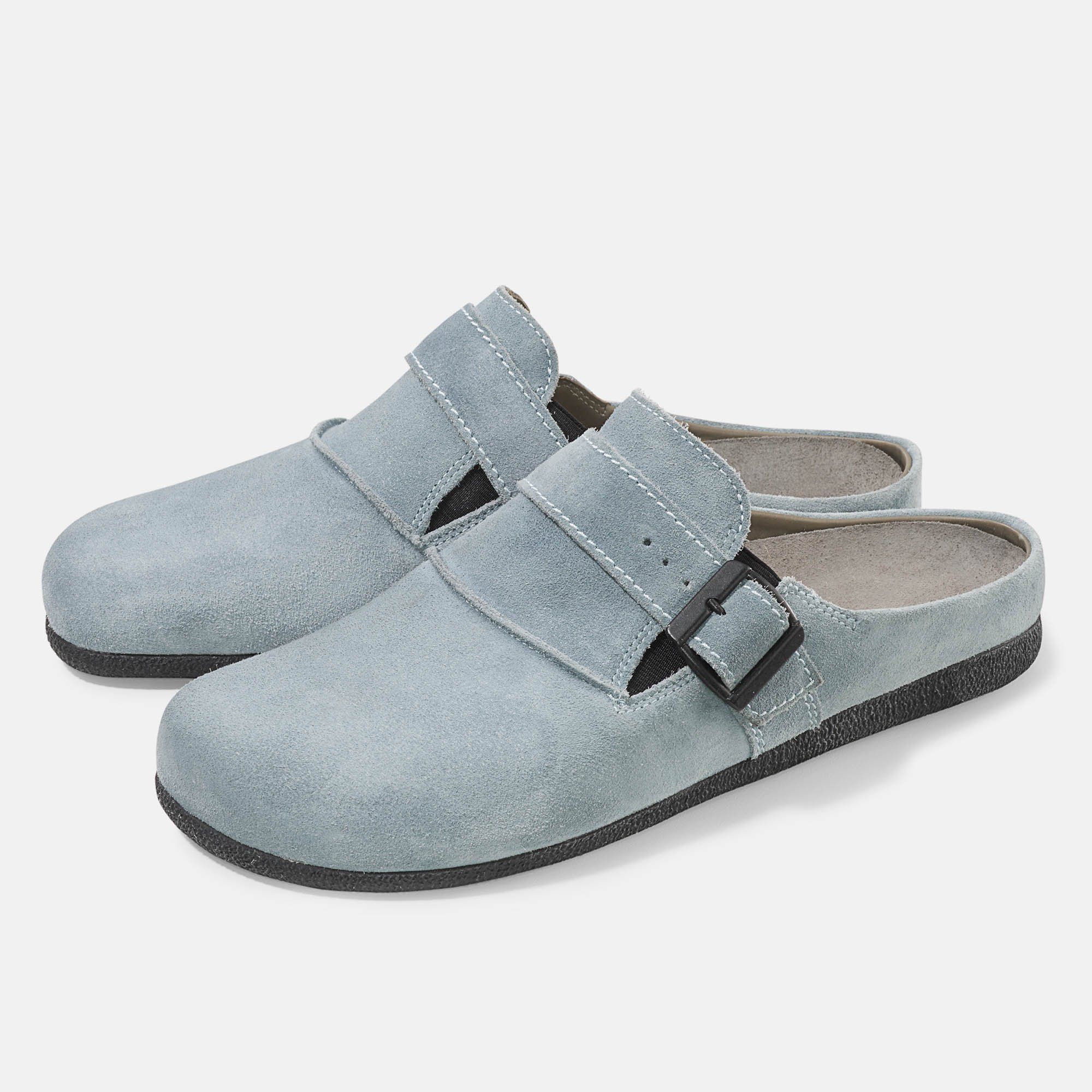 Hellblaue Pantoletten mit Schnalle. Schwarze Sohle. Breite Passform. Zwei Schuhe nebeneinander.