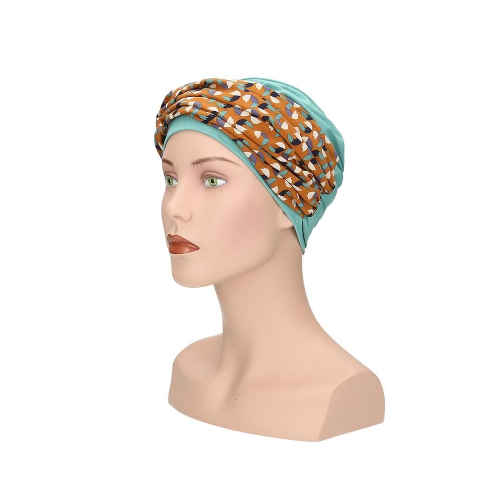 Türkisfarbener Turban mit gemustertem Stirnband auf einer Schaufensterpuppe. Das Stirnband hat ein Muster aus Braun-, Blau- und Beigetönen. Seitenansicht.
