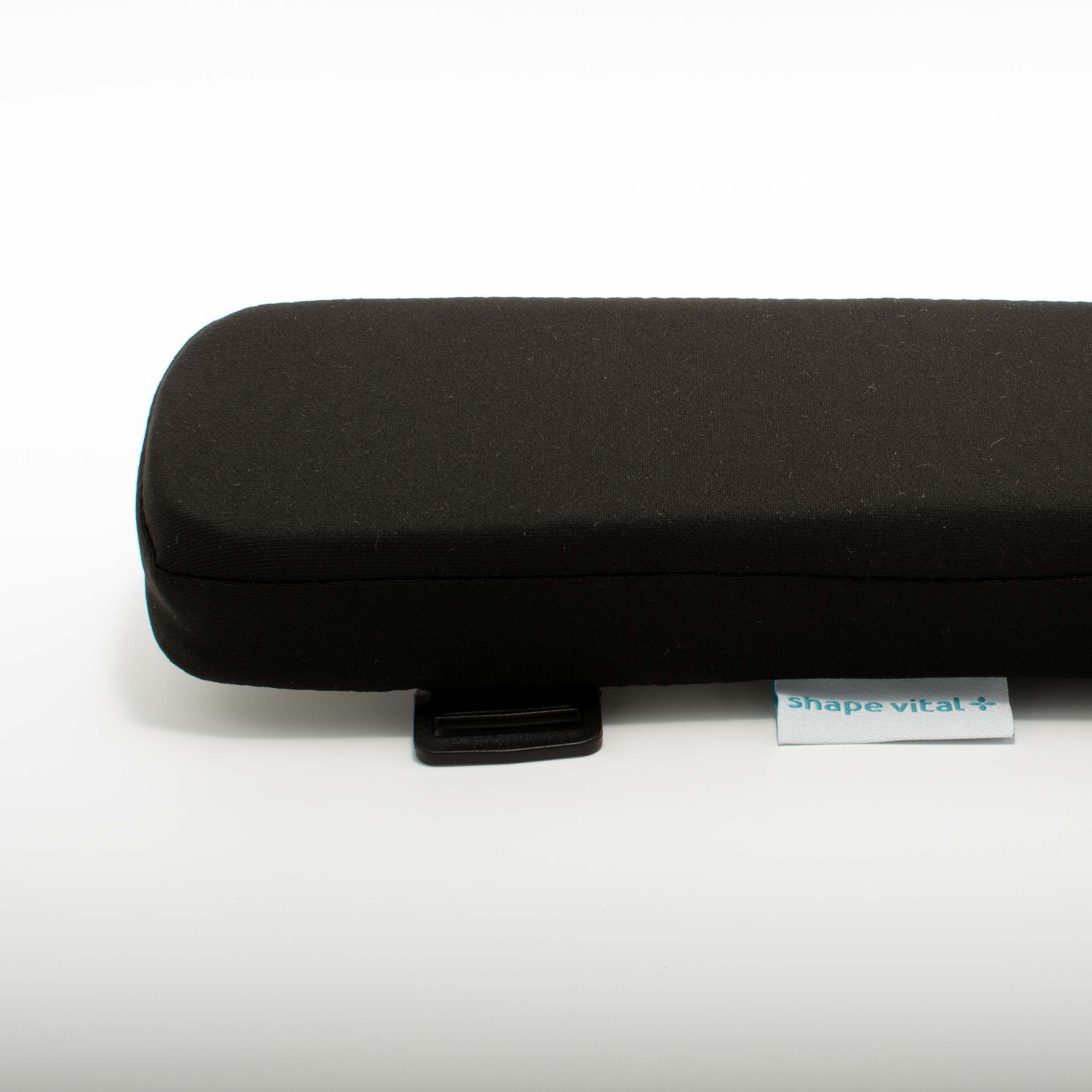Schwarzes Armlehnenkissen mit abgerundeten Ecken. Kleines Etikett mit 'shape vital+'. Schwarzer Befestigungsclip.