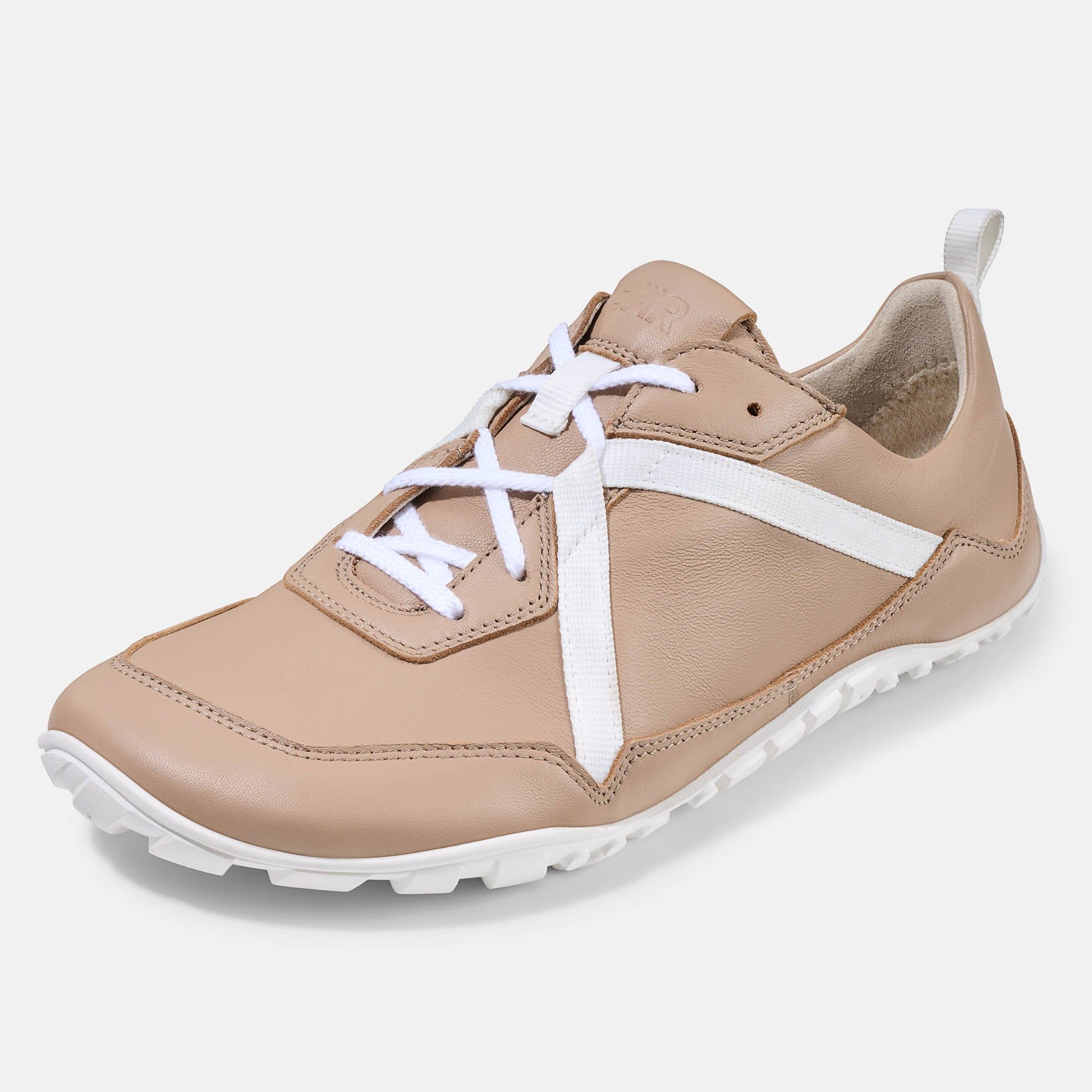 Beige Schnürschuh mit weißen Schnürsenkeln und Streifen. Weiße Sohle. Schuh leicht schräg.