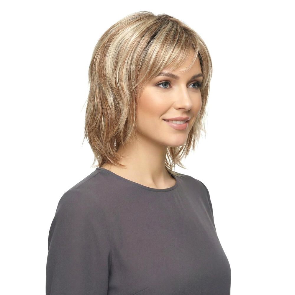 Blonde Perücke, Seitenansicht. Frau mit grauem Oberteil lächelt. Weißer Hintergrund.