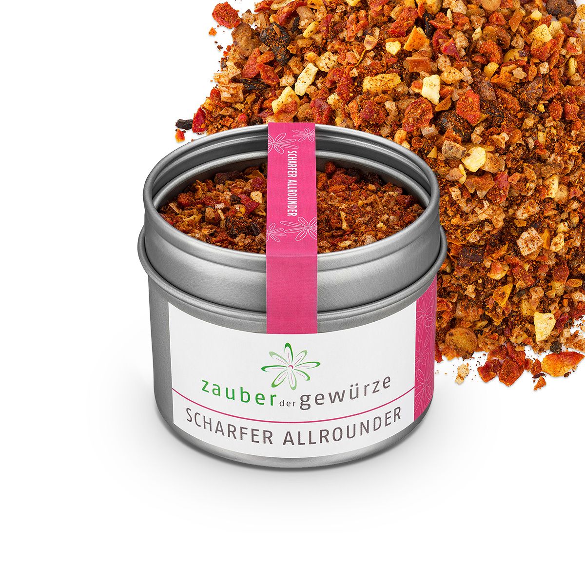 Geöffnete Dose mit Gewürzmischung. Etikett mit "Zauber der Gewürze Scharfer Allrounder". Rosa Band. Gewürze daneben.