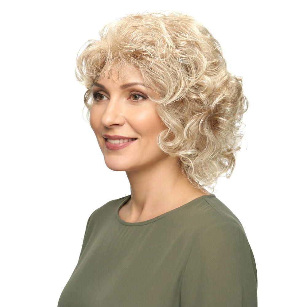 Perücke mit lockigem, blondem Haar. Die Frau trägt ein grünes Oberteil. Seitenansicht.