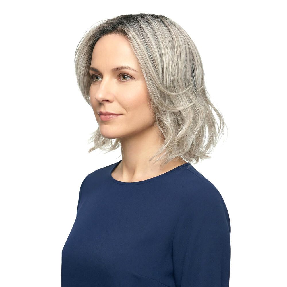 Grau-meliertes, gewelltes Haar, schulterlang. Frau mit blauem Oberteil. Seitenansicht.