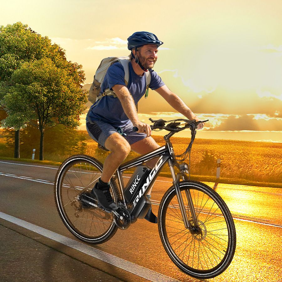 Mann fährt Rincc R200 E-Bike auf Straße. Trägt Helm und Rucksack. Landschaft im Hintergrund.