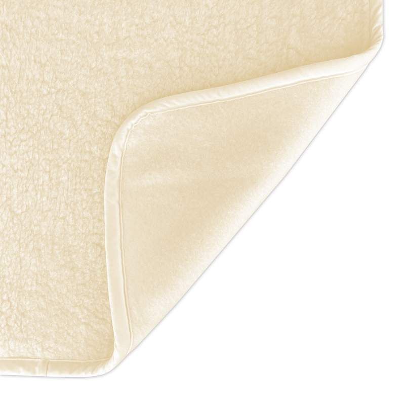 Nahaufnahme: Ecke einer beige Schurwolldecke. Weiche Textur, abgerundete Ecke, weißer Rand.