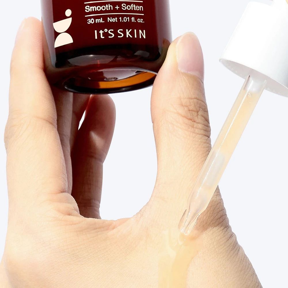 Braune Glasflasche mit Pipette, die Serum auf eine Hand aufträgt.