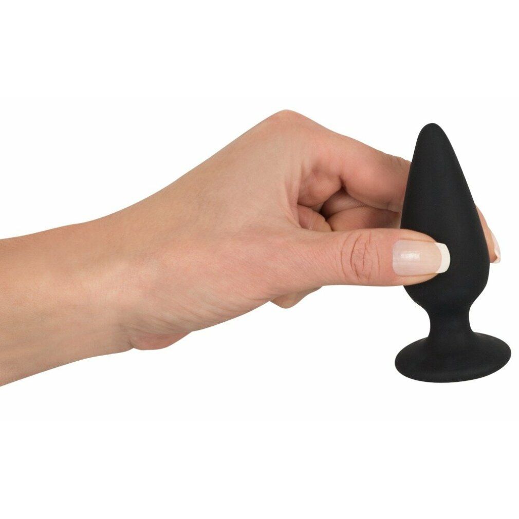 Hand hält schwarzen Analplug. Konische Form, runder Standfuß. Weiches Material.