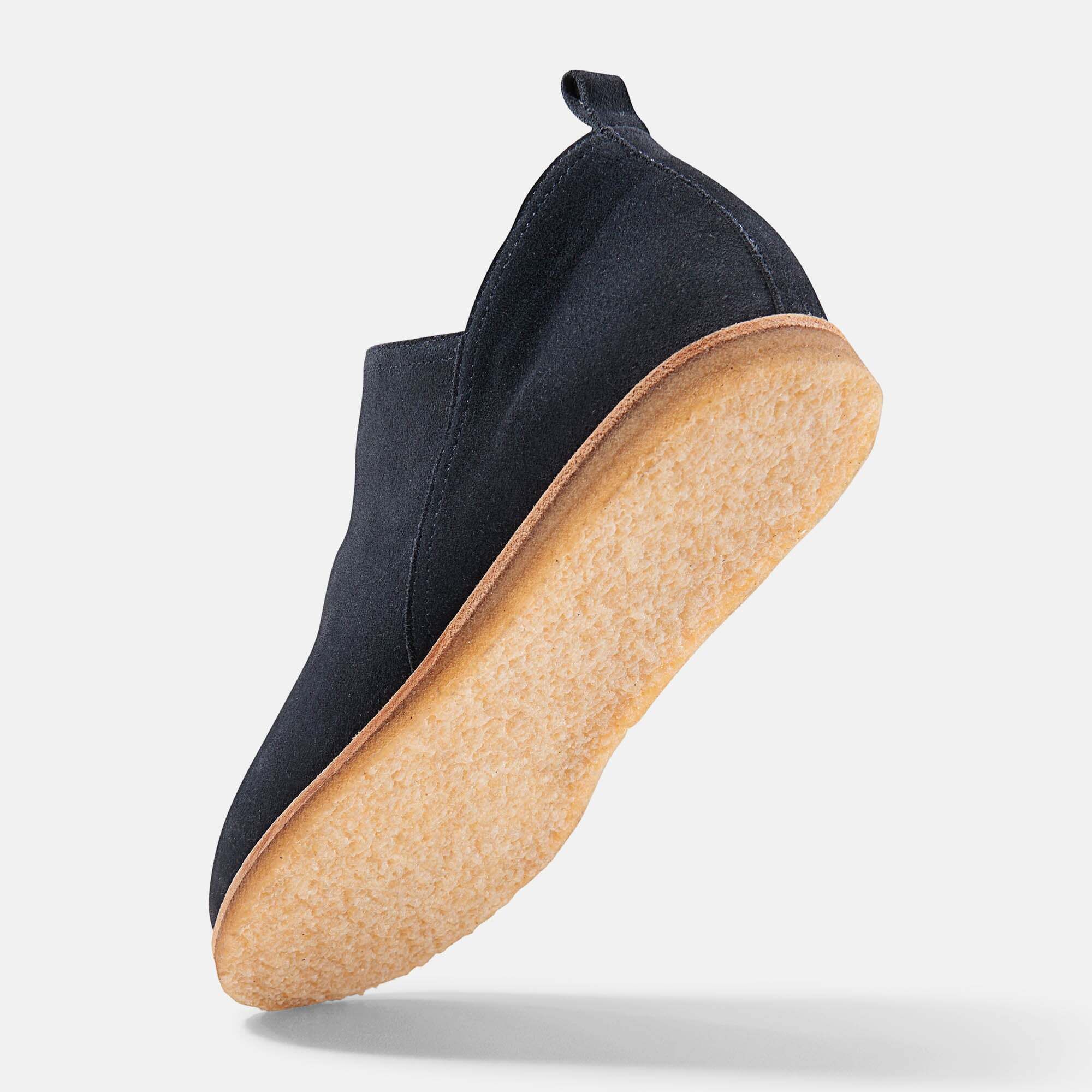 Dunkelblauer Slipper mit breiter Passform. Helle Sohle, Innenfutter sichtbar. Auf hellem Hintergrund. Schuh leicht geneigt.