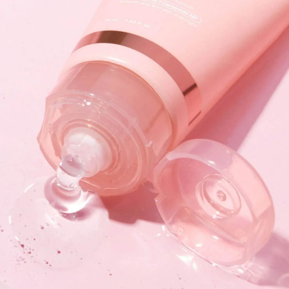 Nahaufnahme einer Tube, aus der eine klare Flüssigkeit austritt. Rosa Hintergrund.