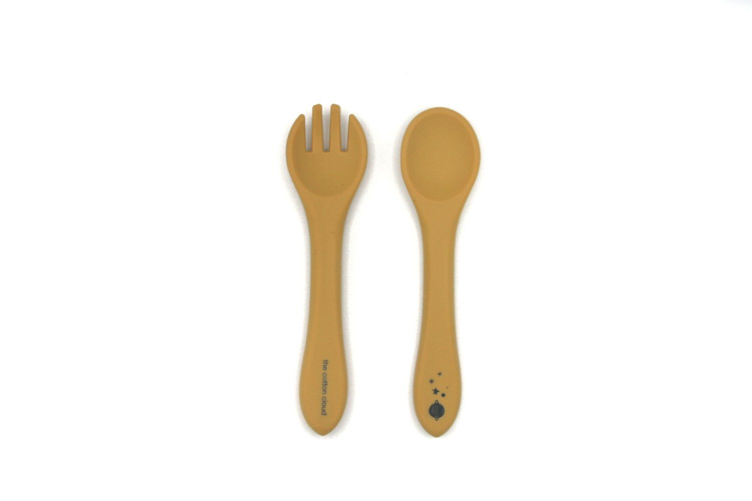 Senffarbenes Besteck-Set aus Silikon. Eine Gabel mit drei Zinken und ein Löffel. Auf dem Löffel ist ein schwarzes Muster.