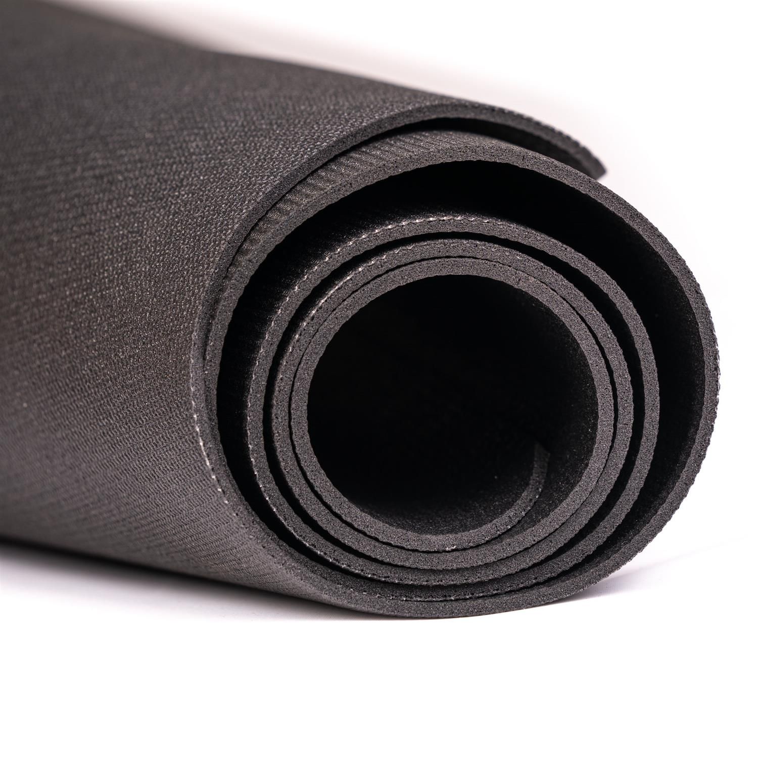 Gerollte schwarze Matte. Mehrere Schichten sichtbar. Weiße Naht am Rand.