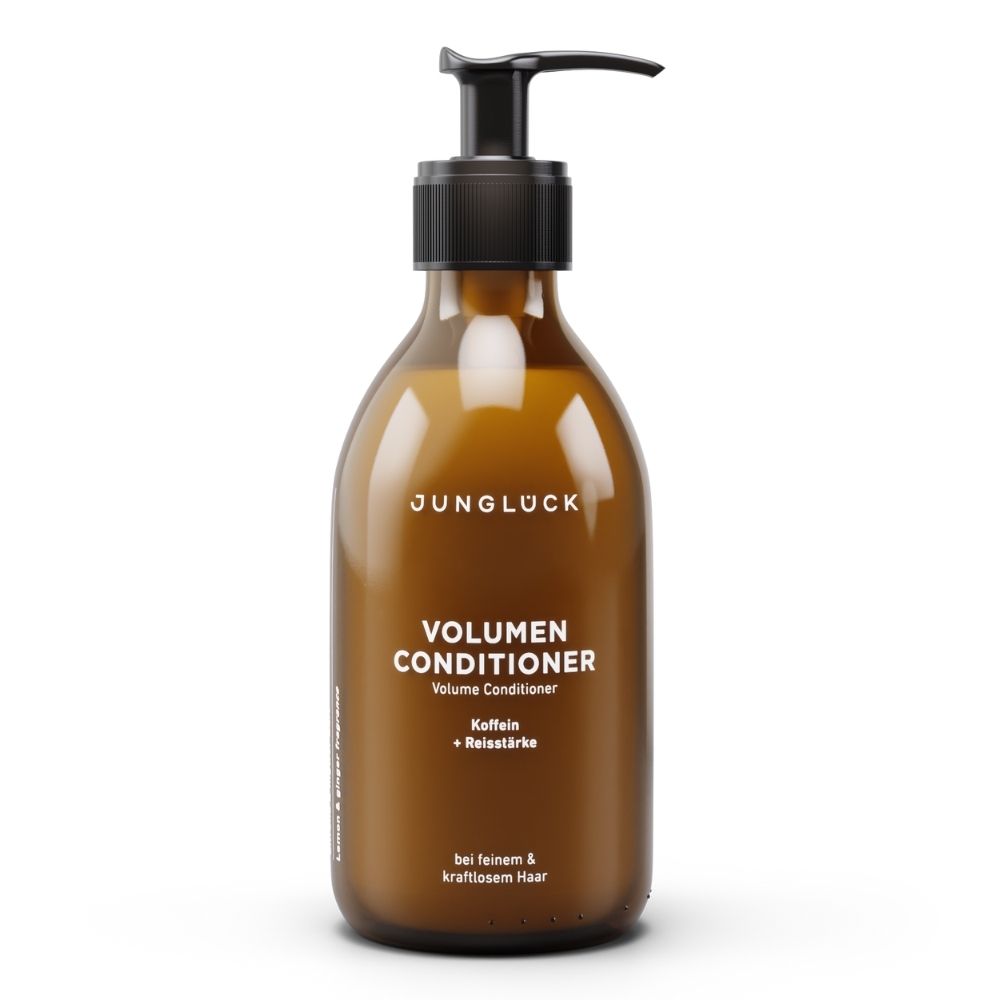 Braune Flasche mit schwarzem Pumpkopf. Aufschrift: JUNGLÜCK, VOLUMEN CONDITIONER, Kaffein + Reisstärke. Für feines & kraftvolles Haar.