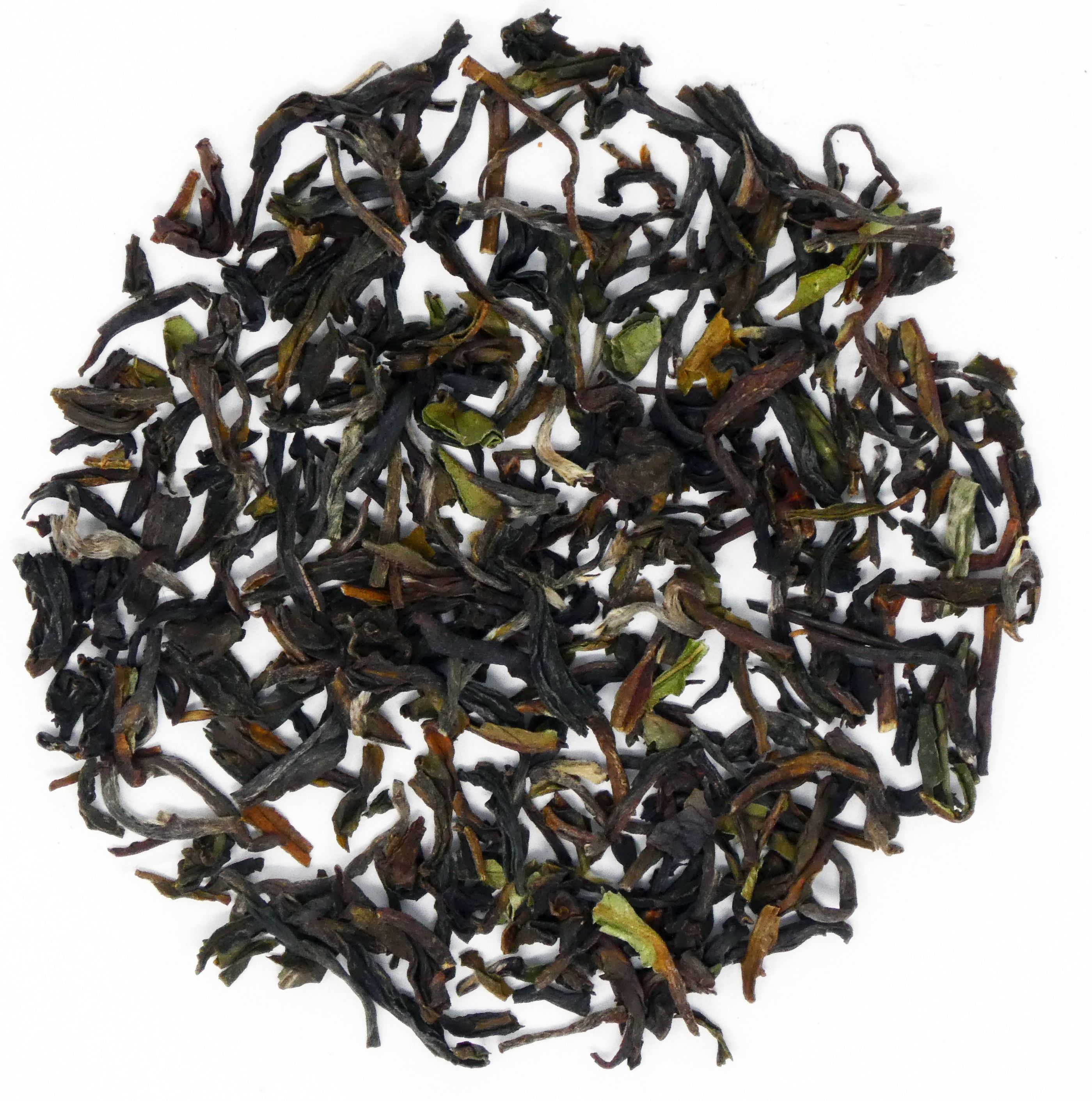 Kreisförmige Anordnung von getrockneten Darjeeling First Flush Tee-Blättern. Dunkelbraun mit grünen Blattspitzen.