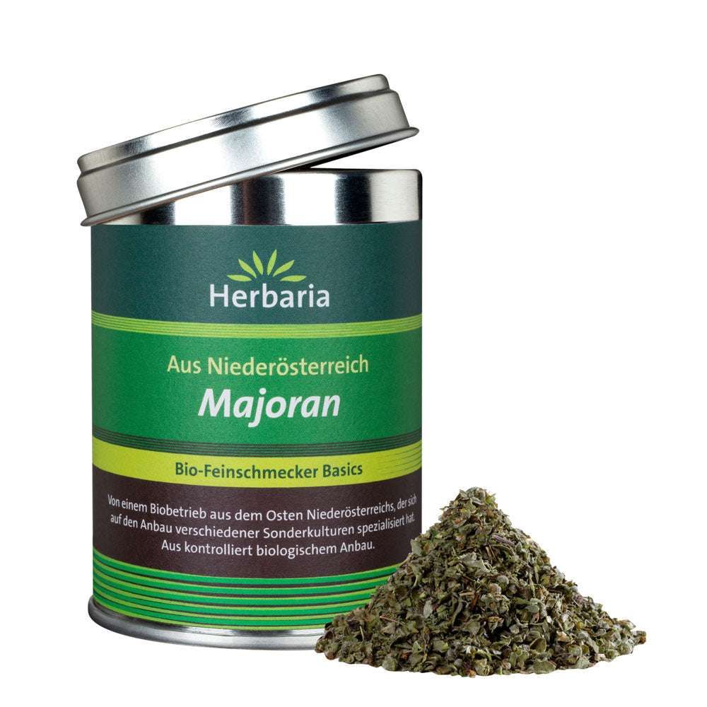 Grüne Dose mit Deckel, Aufschrift "Herbaria Majoran". Daneben ein Haufen getrockneter Majoranblätter. Bio-Feinschmecker Basics.