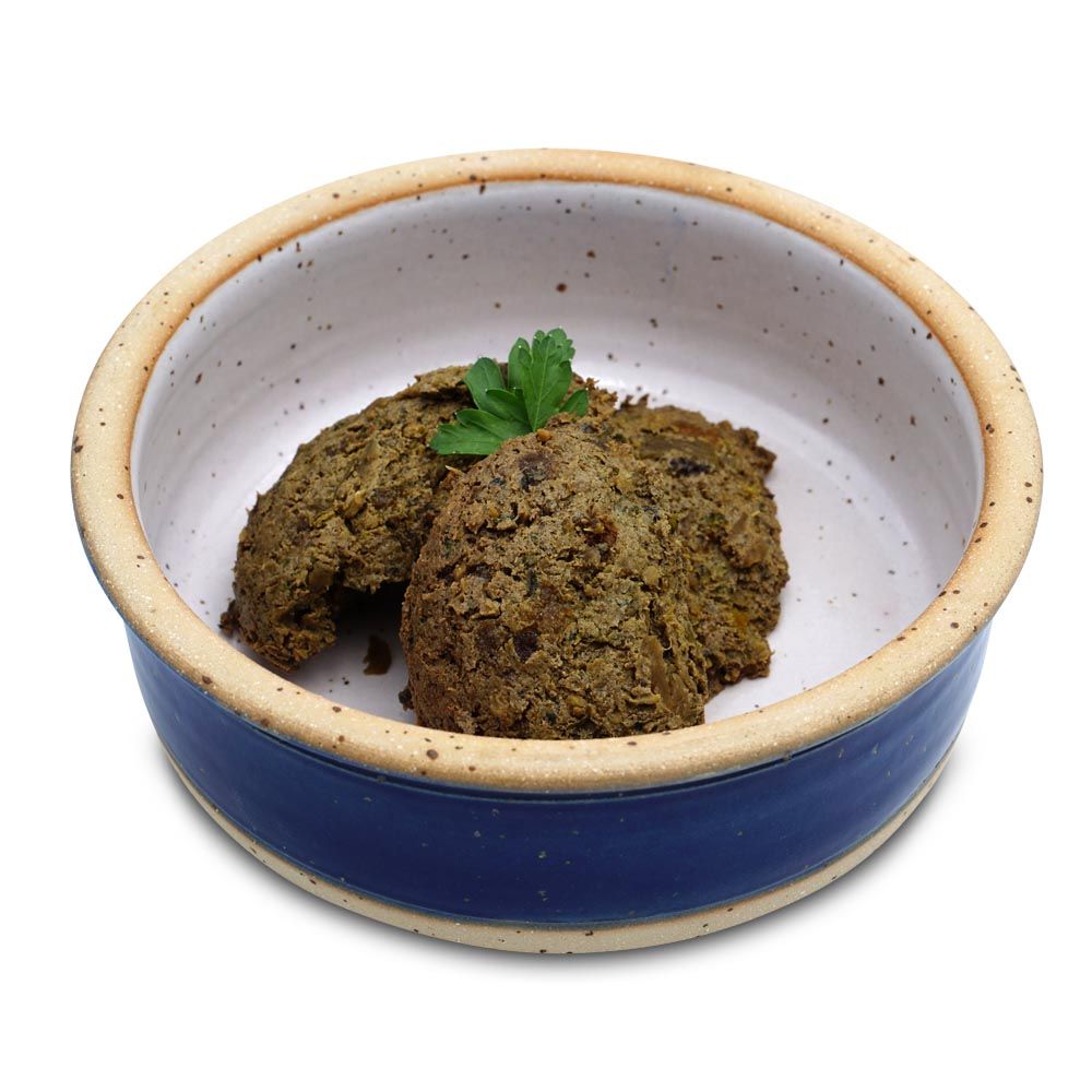 Keramiknapf mit zwei Portionen Futter. Futter grünlich, mit Petersilie garniert. Napf blau-weiß, mit braunem Rand.
