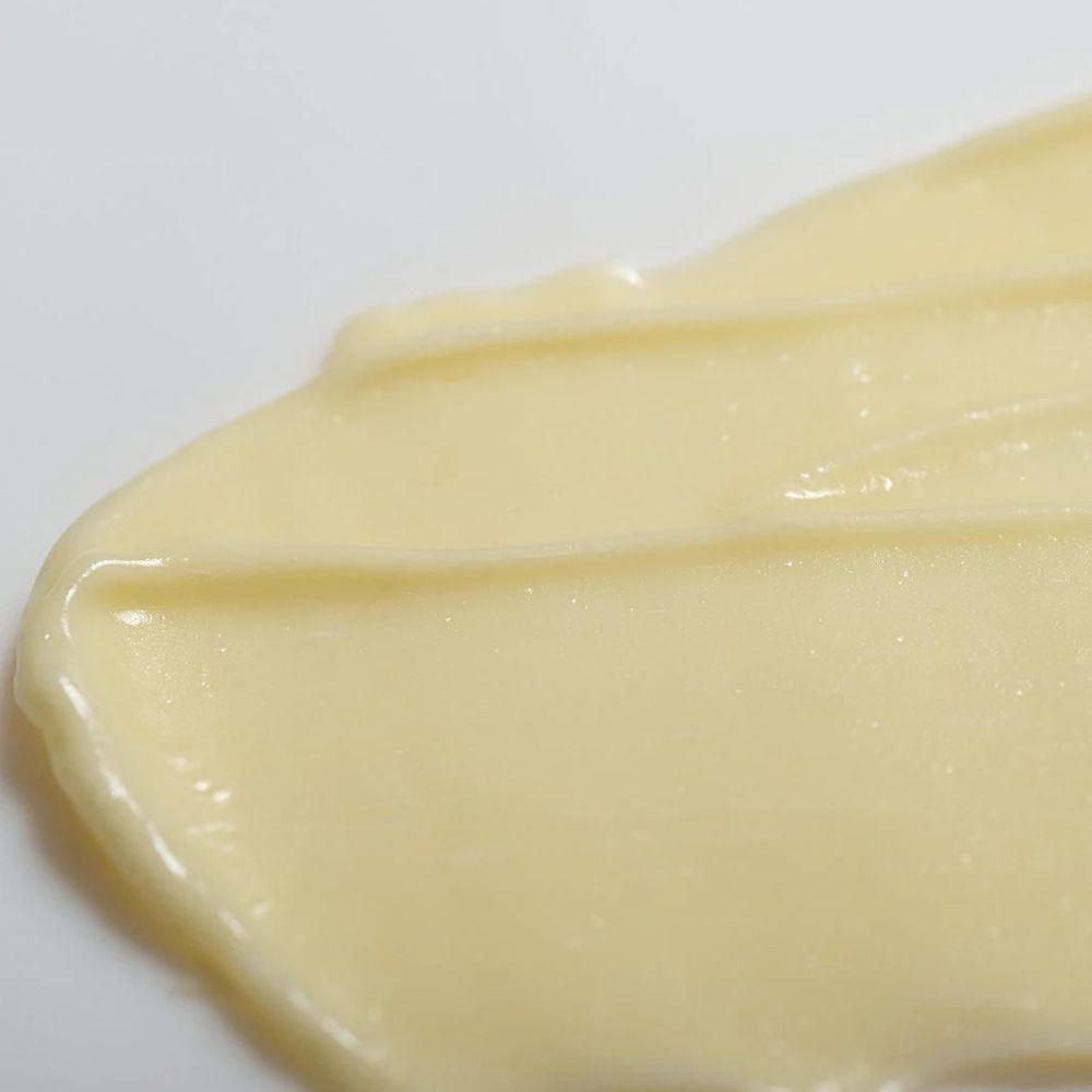 Nahaufnahme einer hellgelben Creme-Textur auf weißem Untergrund.